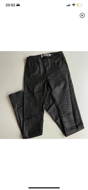 Vaxad byxa XS/32 - Vaxade byxor från Noisy May i storlek XS/32. Smal modell i stretchdenim med blank yta. Infällning fram på låret med sydda, små veck och smala ben samt smala benslut.  Använda men i bra begagnat skick. Mått ca: Midja:72cm Innerben:80cm