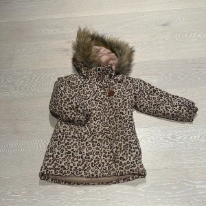 Kuling vinterjacka - Kuling vinterjack, storlek 104 i väldigt fint skick!   Avtagbar huva med en konstpälskant. – Dragkedja framtill. – Justerbar midja. – Två framfickor. – Ficka med dragkedja på bröstet. – Reflexdetalj för bättre synlighet.