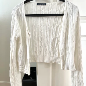 Kofta från Brandy Melville, one size - Söt kabelstickad kofta i en kortare modell från Brandy Melville, one size. Fint skick. Frakt tillkommer 🤍