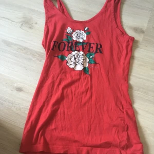 Stl s - Ett rött linne me blommor och en text där det står forever 