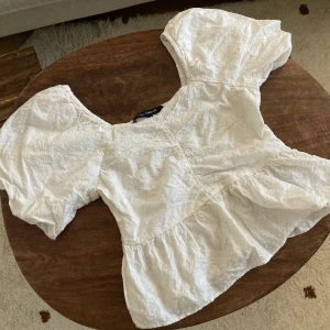 Söt topp med puffärm storlek 38 - Söt vit blus med broderade blommor på med puffärmar. Dragkedja i sidan. Använd 2 gånger. 