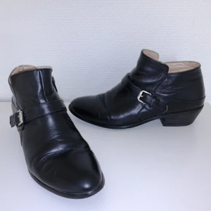 Savannah - Weller svarta skor/boots - Svarta skor i skinn från Savannah. Modellen heter Weller. Storlek 39. Klackarna är ganska slitna baktill och lite av det svarta runt klacken har lossnat. Lädret har spruckit lite upptill i bak vid hälen (höger sko) och det finns en del små märken/repor i lädret (i fram på vänster sko). 