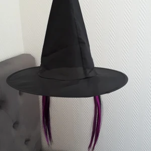 Halloween utklädnad häxhatt  - En svart häxhatt med två svartlila tofsar som går bra att klippa av.