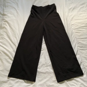 Svarta vida byxor - Väldigt fina svarta byxor som är vida. Sitter smickrande vid lår och rumpa och svänger ut mer vid vader och smalben. Stretchiga så passar även större storlekar