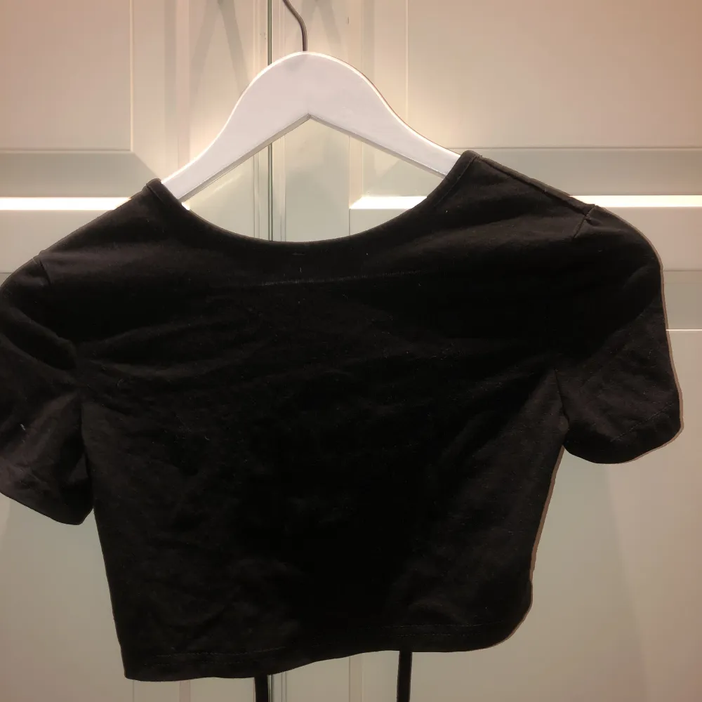 svart t-shirt med öppen rygg som man knyter själv, rätt så croppad vilken blir superfint när man har högmidjat, storleken är xs, aldrig använd då den var för liten för mig💕. T-shirts.