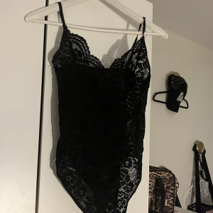 Svart spets body - Fin body att ha över en brallet eller liknande. Knäppe ner till, justerbara band. Pris+frakt, pris kan diskuteras. 