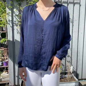 Blå blus - En mörkblå, tidlös och elegant blus som passar till alla tillfällen - kalas, student, skoldag. Blusen faller jättefint och är i bra skick. Gjord på 100% polyester.