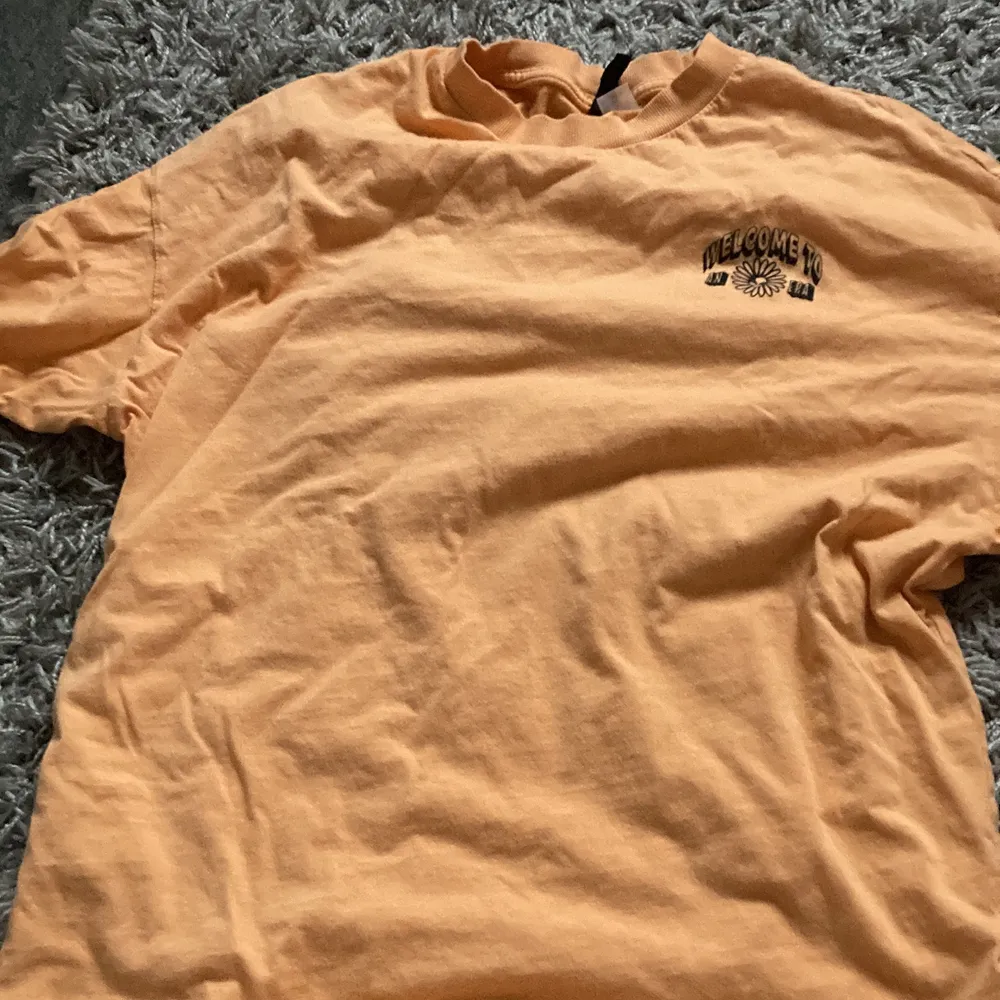 orange t-shirt med tryck både fram och bak. storlek xs men är väldigt stor, ungefär storlek M/L.. T-shirts.