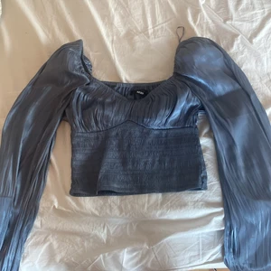 Oanvänd blå blus - Vacker blå blus, sidenliknande material. 