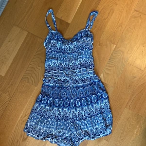 Byxdress  - Söt byxdress i fint skick passar fint till ungdom.  Längd fr v-ringning till gren är 85cm. Bredd över midja 34cm.  Smock i ryggen och reglerbara axelband. 