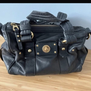 Marc Jacobs väska  - En svart marc jacobs väska med guld detaljer. Köpte den second hand och den är använd men fortfarande i bra skick. Se bilderna. Skriv gärna ifall du har frågor eller prisförslag! 💞