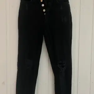 Svarta mom jeans från NA-KD. Hål och sliten design. Knappt använda