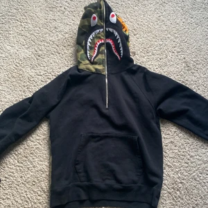 Bape shark wide half zip pullover hoodie - Säljer min bape half zip i storlek L. Är 183 och passar perfekt på mig, samt mina kompisar som är längre men även kortare. Den är i riktigt gott skick med inga skador på tröjan. Tjockt tungt material. Skriv om ni vill ha bilder med tröjan på!                  Kommer inte med kvitto eller tags.          Nypris: 4300kr
