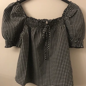 H&M divided rutig blus stl XS - Säljer nu denna fina blus som aldrig är använd! Man kan antingen ha den på axlarna eller som en off shoulder. Det finns även ett snöre på framsidan av blusen och ärmarna är lite puffiga. Tveka inte att höra av dig om du skulle undra något <33