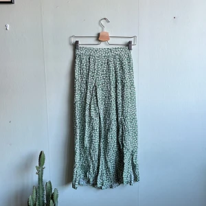 Mönstrad kjol - Grön kjol med blommigt mönster. Har dragkedja och små slitsar. 