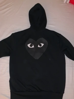 Cdg zip hoodie - En svart Cdg zip hoodie i fint skick, nypris ca 3000kr. Storlek L men passar även M om man vill ha lite större fit på den! Om priset ej duger, lägg ett prisförslag!