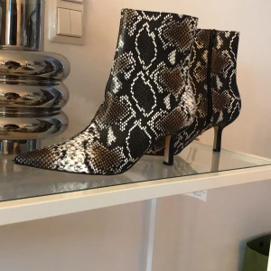 Helt nya boots i ormimitation  - Säljer ett par heta boots med låg klack.  Aldrig använts.  Skorna är i storlek 39 men funkar för dig som har 38 också 