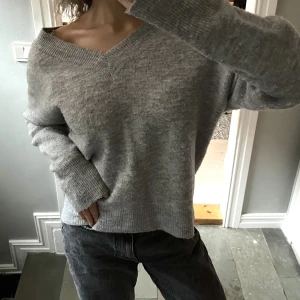 Stickad v-ringad  - Supertrendig tröja i mjukt material och med v-ringad hals, går även att ha som off-shoulder! Jättefin bara till jeans eller över en klänning på sommaren, lite smått noppig men fortfarande i superbra skick.