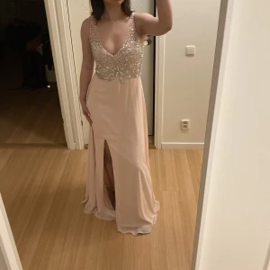 Balklänning - Säljer nu min fina balklänning som använts en gång. De är en ljusrosa klänning med slits på vänstra benet. Dubbelfodrat runt bröstet med en lätt pushup och pärlor, paljetter och stenar från midjan och uppåt. Köptes för 2000kr skräddarsydd.