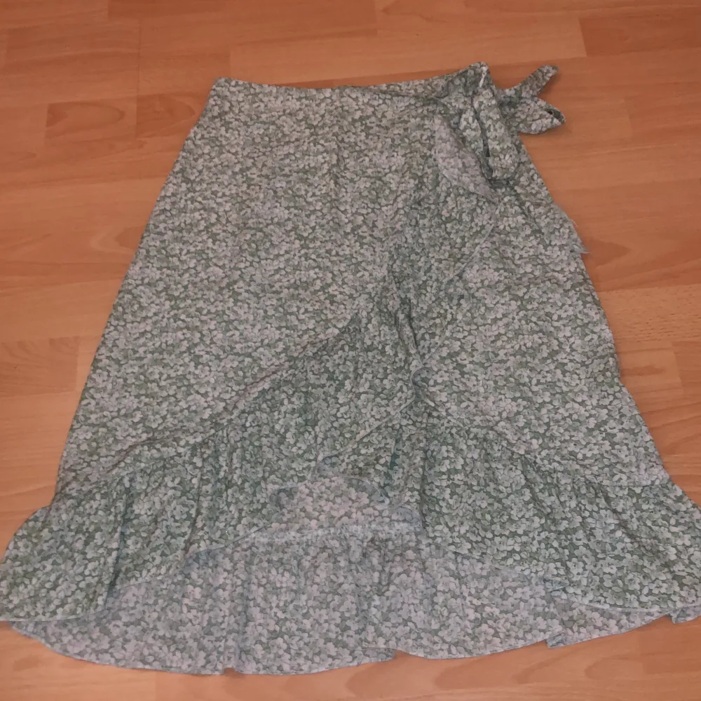 En grönblommig kjol från SHEIN, storlek S men passar mig som oftast har storlek M. Har en dragkedja på samma sida som knuten.. Kjolar.