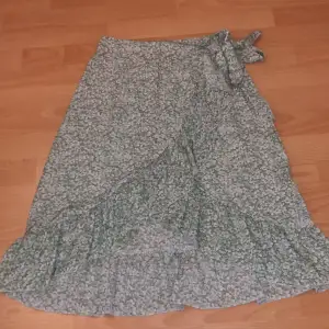 En grönblommig kjol från SHEIN, storlek S men passar mig som oftast har storlek M. Har en dragkedja på samma sida som knuten.