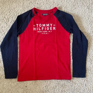 Långärmad tommyhilfiger T-shirt stl 152 - Röd långärmad Tommy hiliger T-shirt med marinblåa armar. Bra skick stl 152. Köparen står för frakten. Inget återköp