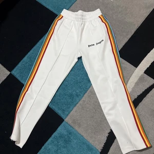 Palm angels byxor  - Vita palm angels byxor med 6 olika färger på sidan av byxorna. Väldigt fina och oanvända då dom bara är använda i få tillfällen. Köpt för 3200kr, kvitto finns.                                                     HÖR AV ER VID FRÅGOR ELR FLER BILDER