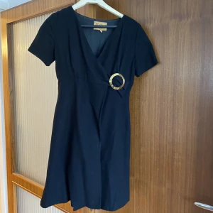 Klänning - Svart omlottklänning med spänne