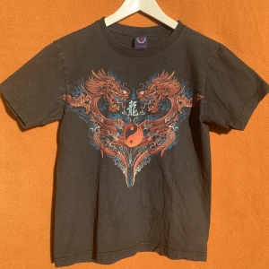 Svart T-shirt med draktryck - Svart bomulls t-shirt med draktryck på både fram och baksida. Om du har frågor eller vill se fler bilder är det bara att skicka iväg ett meddelande:)