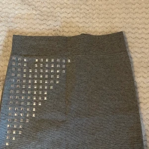 Kjol med nitar - Superfin kjol med nit-detaljer på framsidan. Slutar ovanför knäna (är va 170) om jag har den högmidjat. 