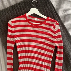 Tröja från Filippa K i silke/kashmir/ull - Randig (röd och ljusrosa) tröja från Filippa K i kashmir, silke och ull-blandning. Storlek S. SÅ MJUK! Välanvänd av mig men fortfarande fint skick. Guldknapparna som sitter på ena axeln har blivit lite slitna (se bild).