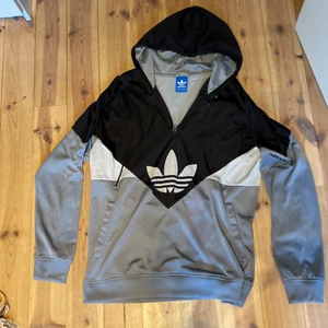 Adidas, tjocktröja storlek XL - Baggy tjocktröja i lite glansigt material med decimeterlång dragkedja över märket på bröstet. 