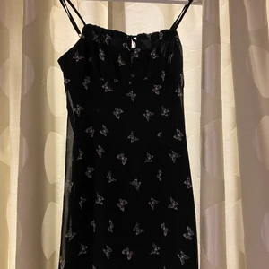 Svart klänning  - Svart klänning med fjärilar och en fin Knut detalj vid brösten. Kommer tyvärr inte till användning men i bra skick! 