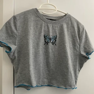 Grå t-shirt med fjäril på  - Söt grå t-shirt med en fin blå fjäril på 🦋🦋 Har användts en gång :) 