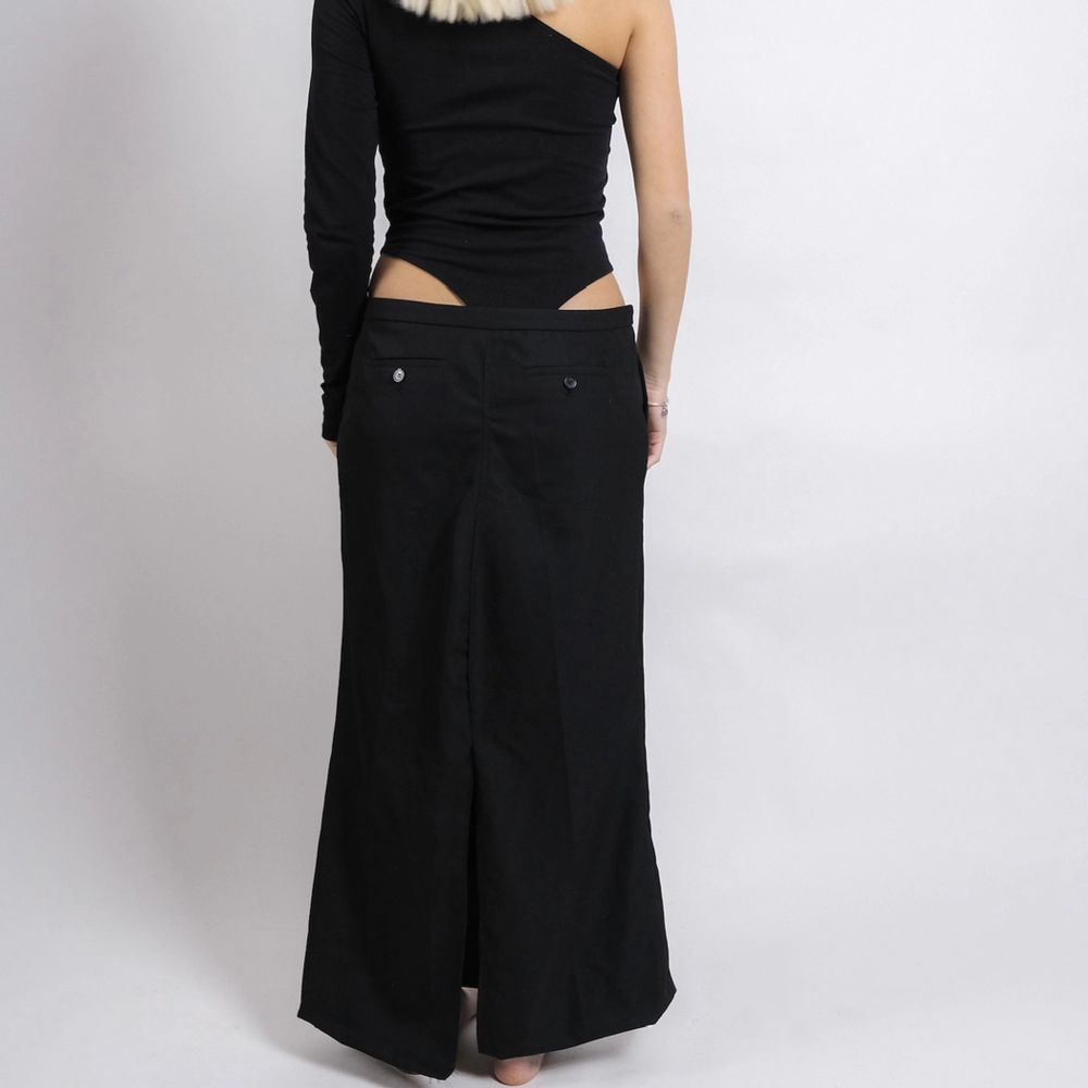 En svart långkjol i kostym material. Kjolen är omdesignad från ett par kostymbyxor till en kjol. Modellen på bilden är 170 cm och bär stl S/M. Passar både större som mindre beroende på önskad passform.  Storlek: M/L. Kjolar.