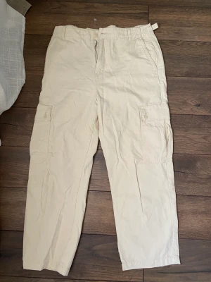Cargopants Pull & Bear - Beige/offwhite cargobyxor från Pull & Bear. Använda bara 5 ggr. Något kortare modell i benen. Är i storlek 42 men sitter snarare som 38/40. Perfekt oversize om du är 36/38. 