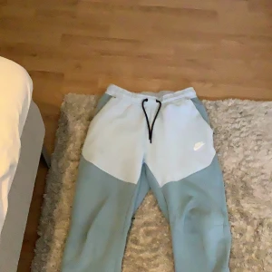Ljusblå nike tech byxor storlek S 💙 - Säljer för att jag inte använder de. De har en liten slitning på knät men det syns knappast och det är därför jag säljer de billigt. Annars är de som nya 💙