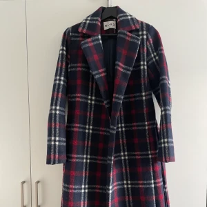 Kappa från NA-KD - Kappa i fint skick från NA-KD, säljs för att den inte kommer till användning. Den är lång i passformen och kommer med ett skärp/knytband.