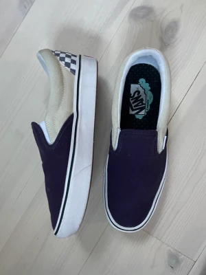 Vans slip-on stl 39 - Vans i lila och lilarutig canvas med mocka på sidorna i stl 39. Nypris 549 önskar 100 kr. Använda en gång.