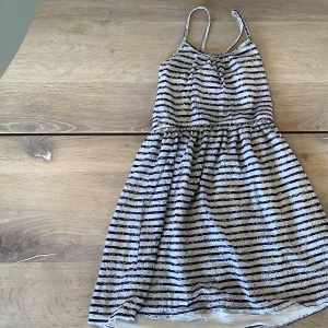 Klänning  - En fin klänning i färgerna mörkblå och vit, det är ett dubbla tyg och fina hålmönster. Den kommer från H&M och är från 8-10år 