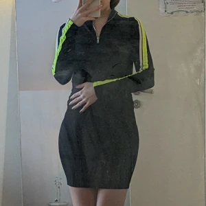 Snygg klänning - Använt en gång! Har neongröna stripes på ärmarna och sitter figurnära.