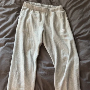 Nike grå mjukisbyxor - Tjo, jag säljer mina Nike gråa mjukis byxor. Otroligt snygga och fel fria. De är ett par byxor utan mudd där nere vilket jag tycker är sjukt snyggt. Brallorna är i strl M och sitter bra på mig som är 181 cm!👍🏻👌🏻🙌🏼