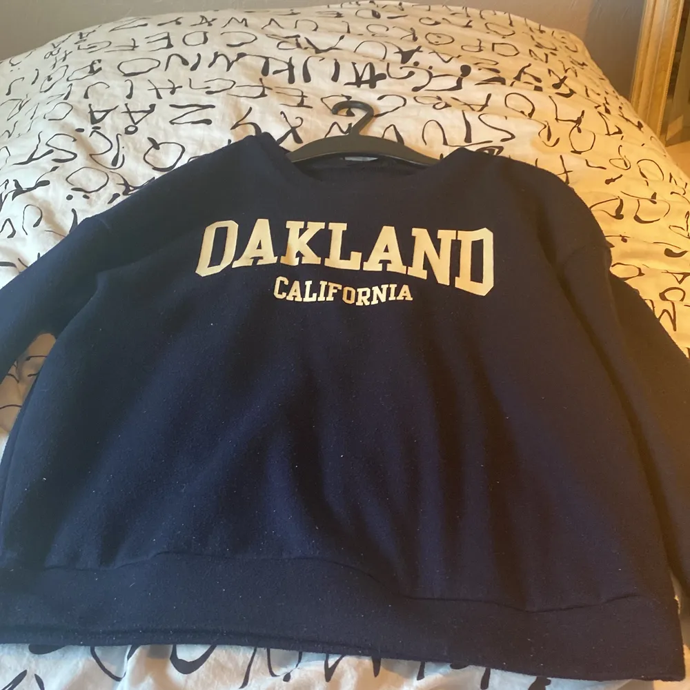 En super fin mörkblå sweetshirt där det står Oakland. Lite prickig men ingen som syns på långt håll. . Neuletakit & Villapaidat.