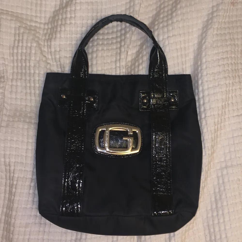 en handväska från guess köpt secondhand i färgen svart. Väskor.