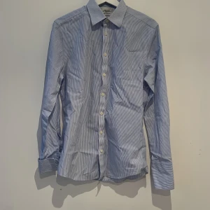 Sommar skjorta  - En bra dressad sommarskjorta. Tunn men med klass. Blåa och vita ränder. Dubbelmanschett som är snyggt på sommaren. Alldrig använd 