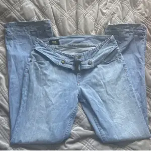 Superfina lågmidjade, utsvängda jeans från Lee köpta second hand. De har ett coolt bälte fastsytt och hade gärna behållit dem om de inte var för korta på mig som är 184. Aningen slitna nere vid hälen.  Midjemått: 39,5cm mätt rakt över Innerbenslängd: 80cm