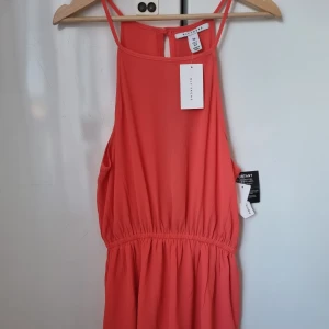 Korallfärgad playsuit - Korallfärgad playsuit med öppen rygg. Aldrig använd, med lapp kvar. Passar S/M 🌸  (Frakt/porto kan diskuteras)