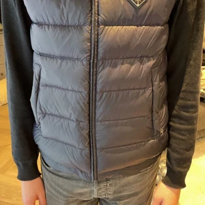 Prada väst - Äkta Prada ”nylon logo vest” säljes. Litet hål på västen Se bild 3 annars helt felfri. Nypris 11500 