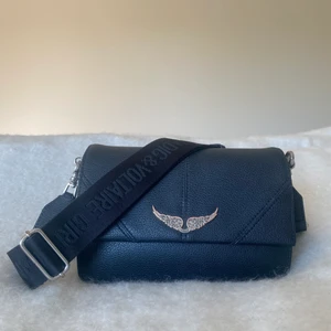 Zadig et Voltaire väska - Säljer denna svarta Zadig et Voltaire väska köpt i London (på Selfridge) år 2019. I gott skick och nypris var 2 895kr. Säljer då den inte kommer till användning. Rymlig och går även att byta band. 