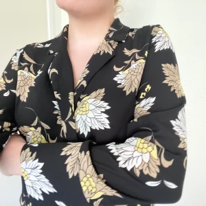 Blommig blus - Denna blommiga blus har ett kavajliknande utseende men materialet är som en blus! En skön blus att ha till vardags eller finare tillställningar. Sitter snyggt och skönt! Använd ett fåtalet gånger💖